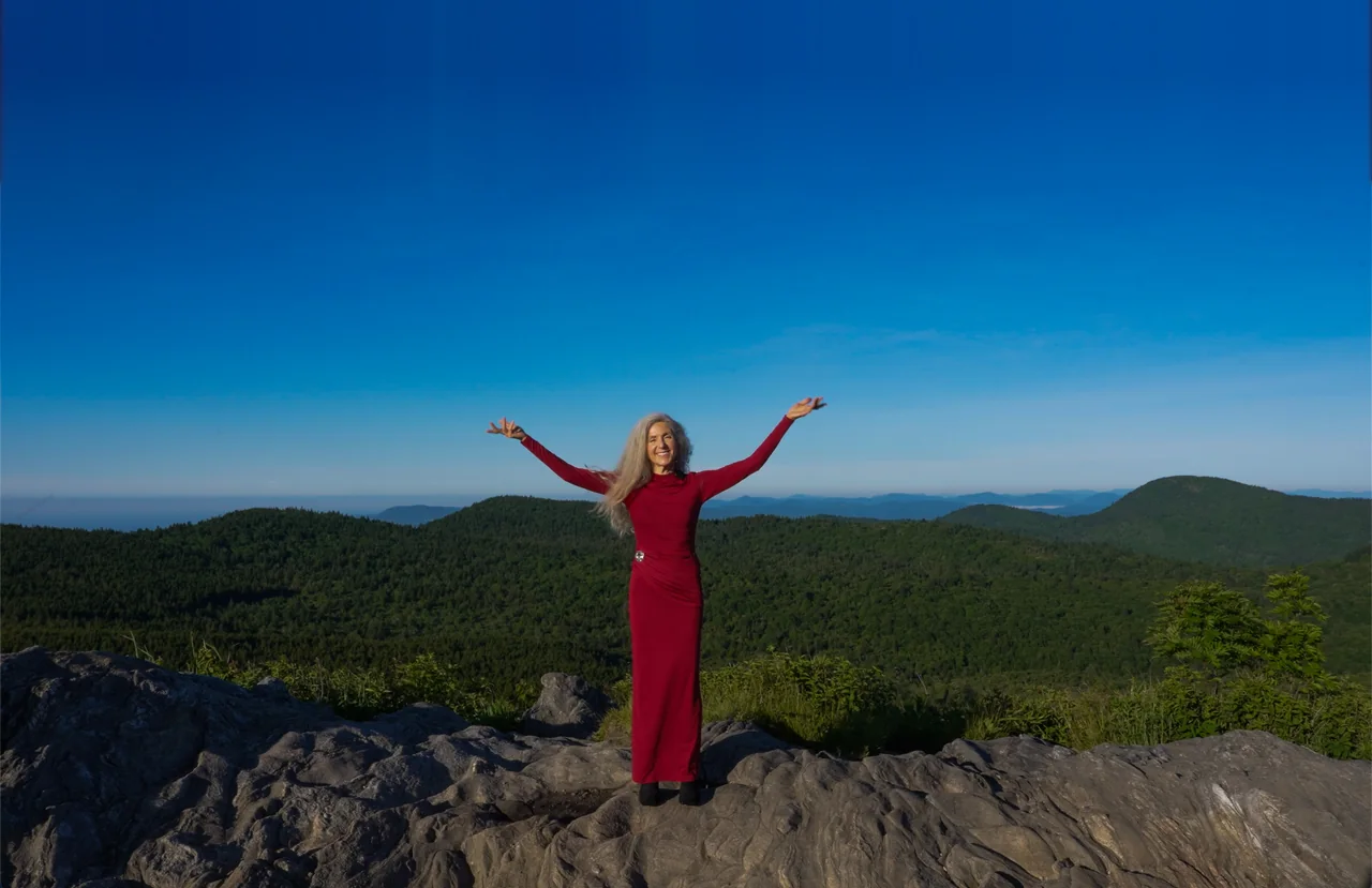 Iana Lahi, arms open on a mountain summit