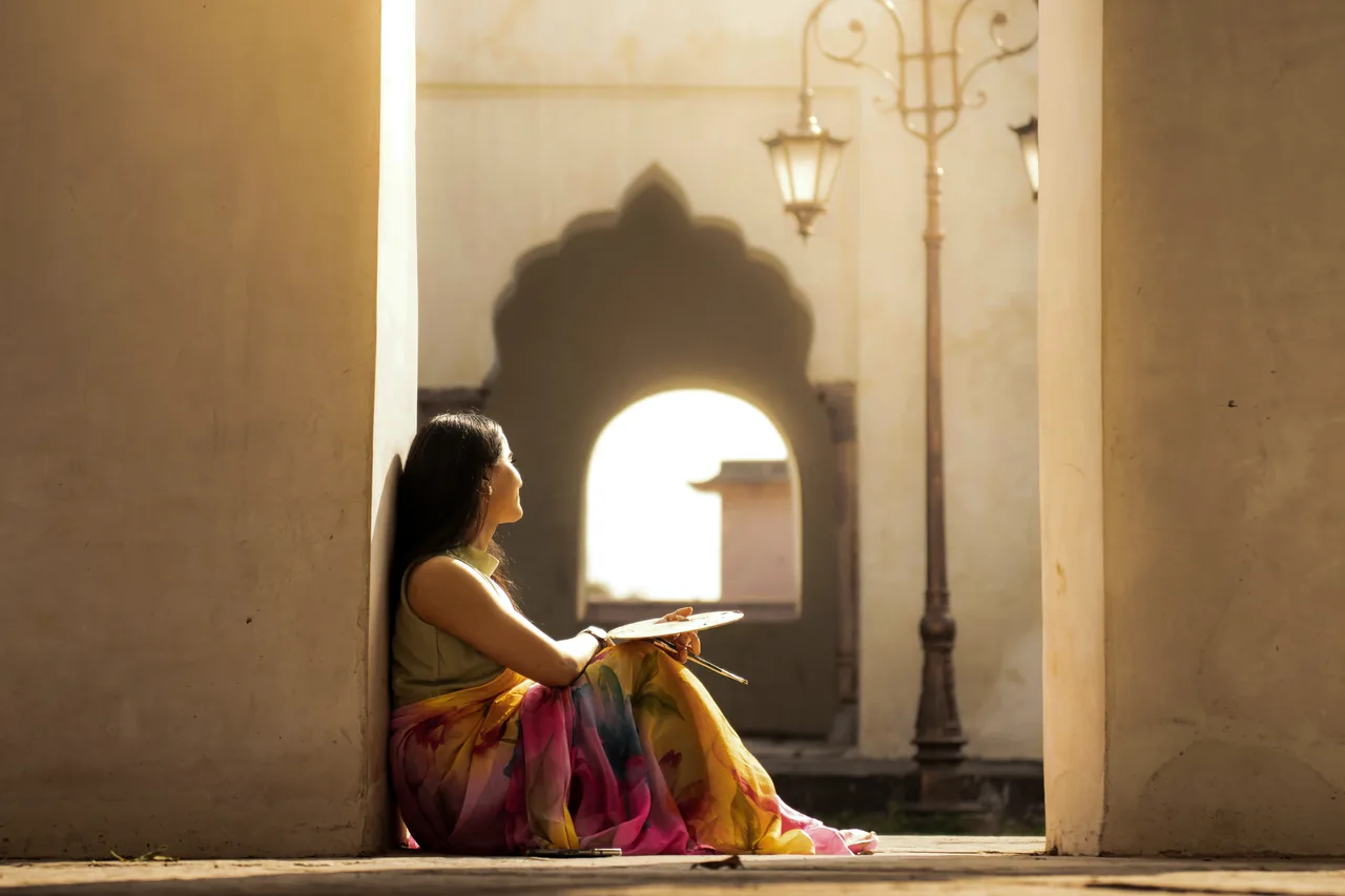 A woman sitting alone in a sunlit archway