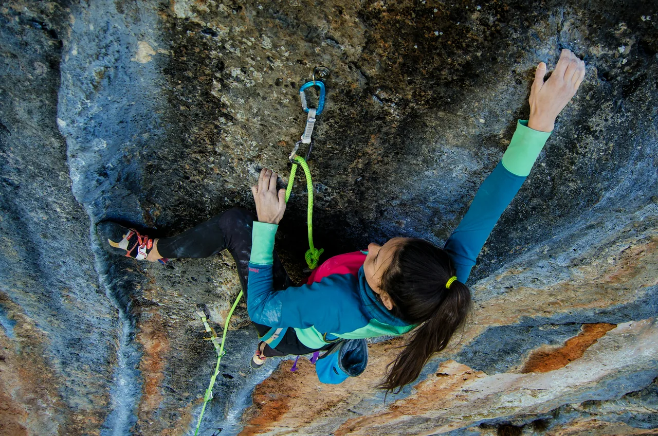 A woman climbing an overhanging rock face