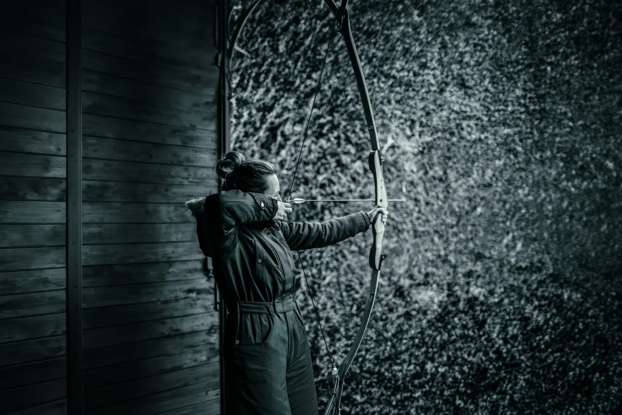 A woman drawing her bow, arrow at full draw