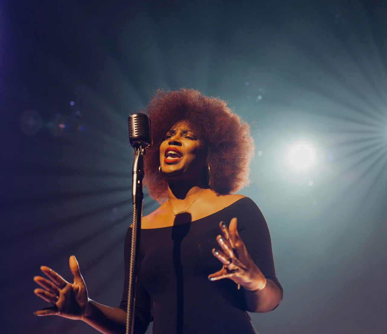 A woman singing into a microphone, lit from behind