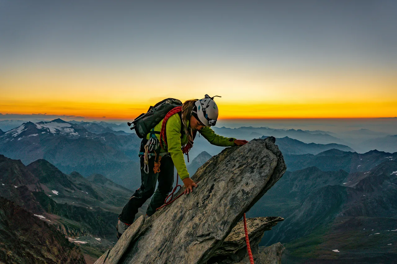A climber reaching the summit at dawn