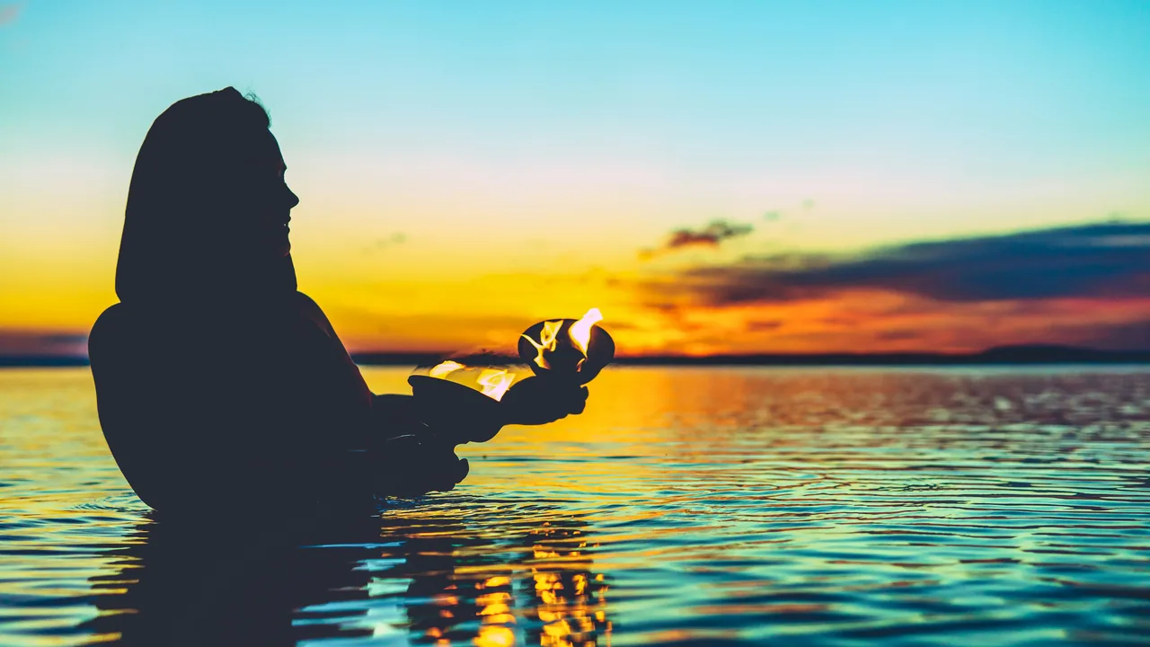 A woman in silhouette in the sea at sunset